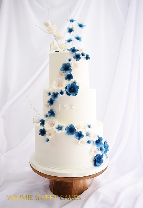 Een bruidstaart met blauwe suikerbloemen